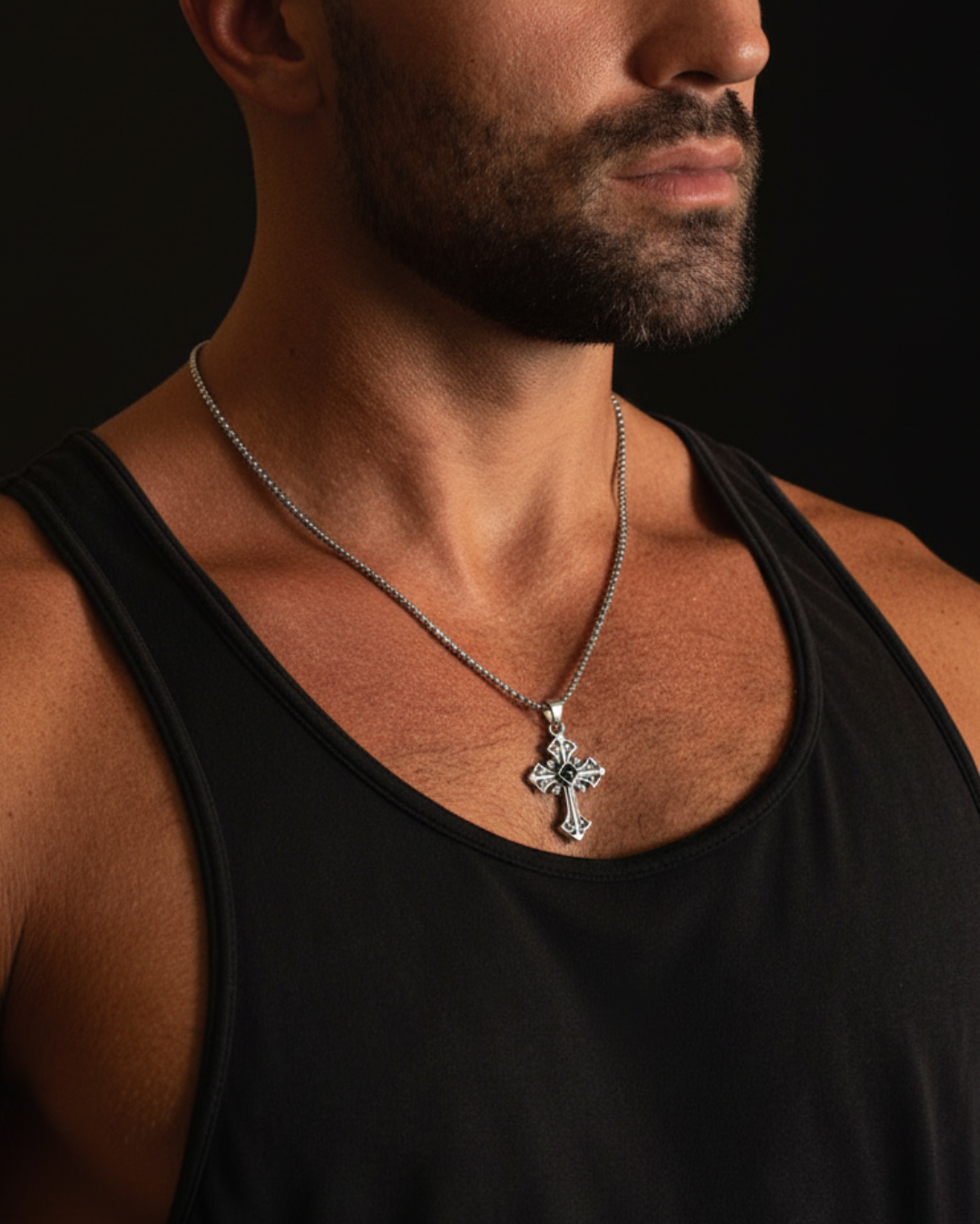 Man wearing a black tank top with a silver necklace featuring a Darkstone Cross Pendant against a dark background