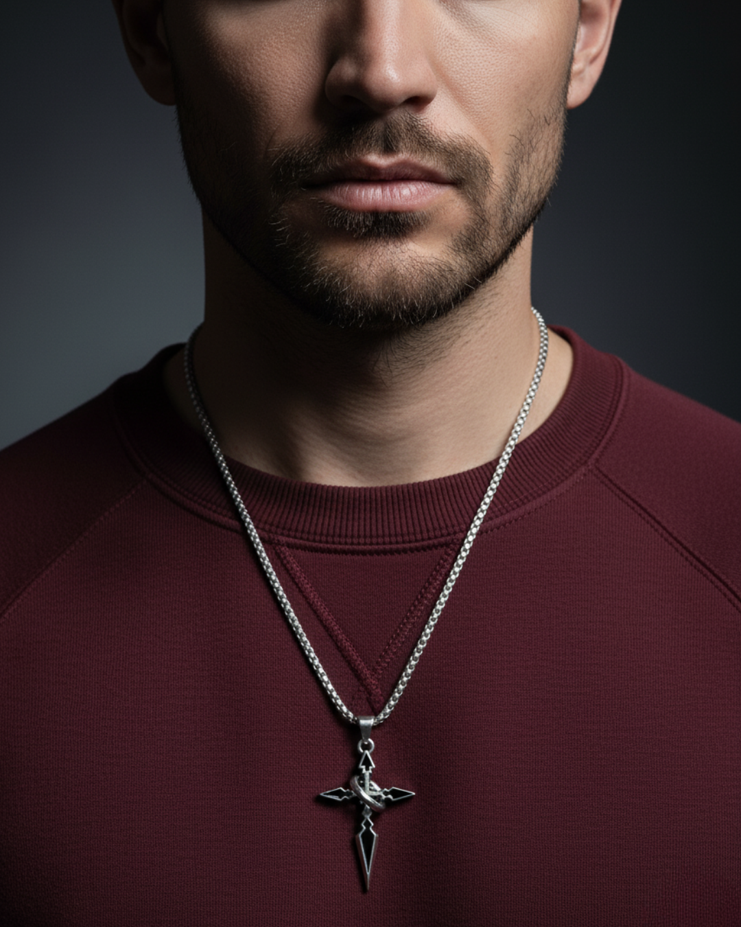 Man wearing a maroon sweater with a silver necklace featuring a Night's Compass Pendant against a dark background