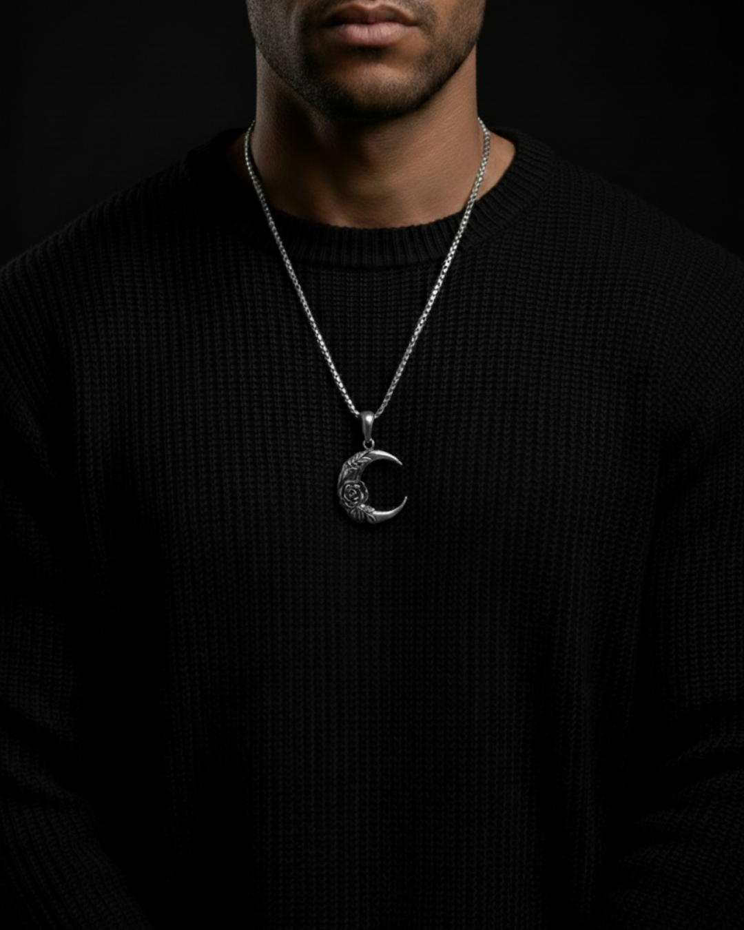 Person wearing a black sweater with a silver necklace featuring a Midnight Rosemoon Pendant on a dark background